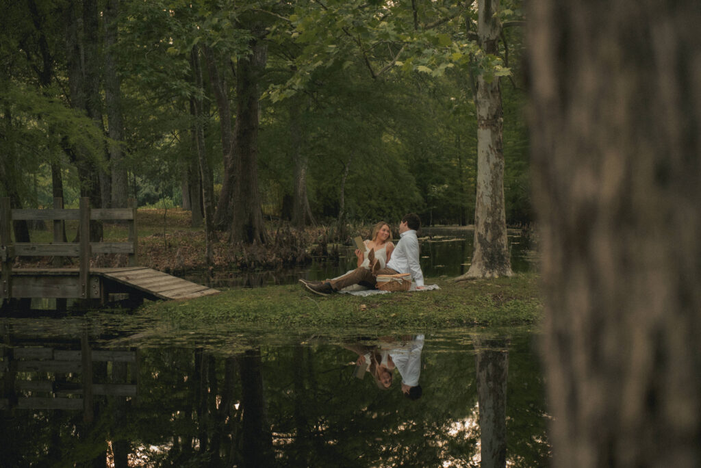 Wide photo of an engaged couple having a picnic by the water in a Houston park.