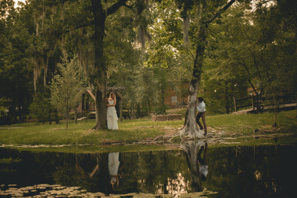 Playful engaged couple portrait around a tree in a wooded Houston park.