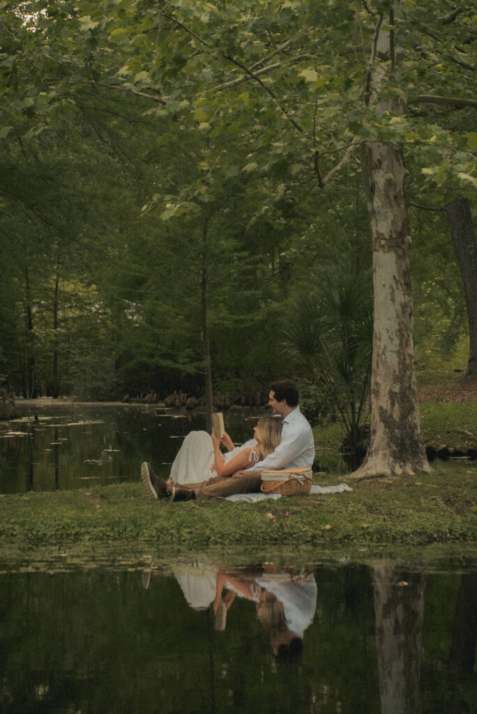 Engaged couple relaxing and reading on a blanket during a Houston park session.